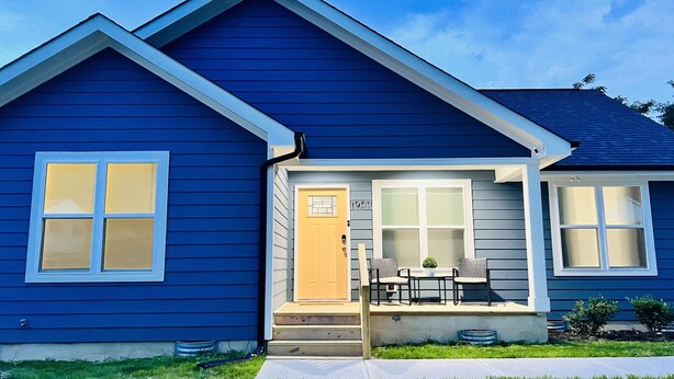 Une maison bleue avec un porche à l’avant, une porte et une boîte aux lettres.