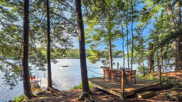 A wooden deck with chairs overlooking a lake, surrounded by trees. - Quintessential Maine cabin w/ private waterfront (Augusta)