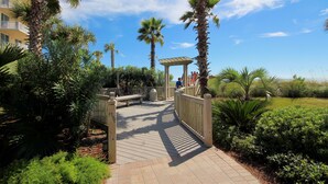 A wooden boardwalk leading to a gazebo with people sitting.
