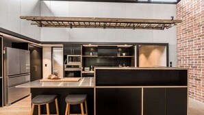 Een moderne keuken met een centraal eiland, barstoelen en een bakstenen muur.