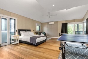 A modern bedroom with a bed, bedside table, and a ping pong table.