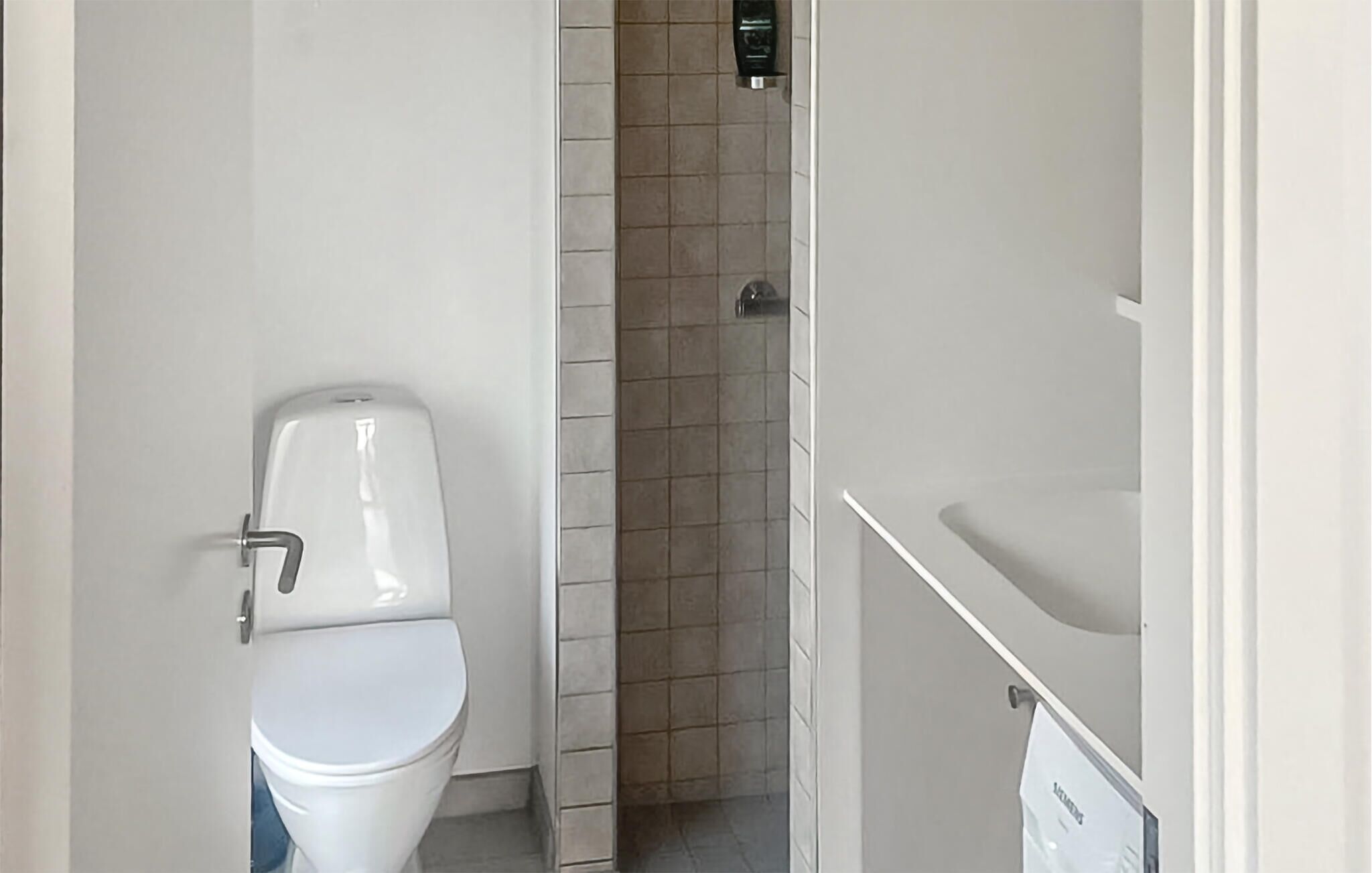 Een badkamer met toilet, douche en wastafel.
