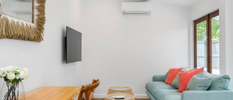 A modern living room with a sofa, a TV, a wooden table, and a wicker coffee table.