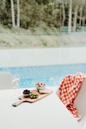 A table with a wooden board holding a bowl of berries, a bowl of olives, and a wooden board with a checkered towel.