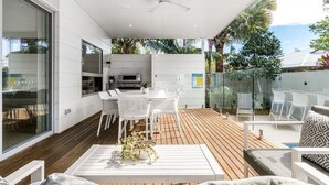 An outdoor patio with a dining area, white furniture, and a ceiling fan.
