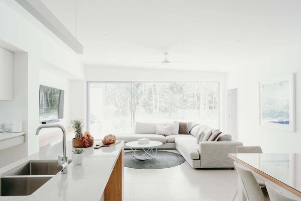 A modern living room with a sofa, coffee table, and a dining area with chairs.