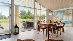 A dining area with a wooden table and chairs, large windows, a map on the wall, and a lantern on the floor. - Pet friendly home in Saltum with WiFi (Saltum)