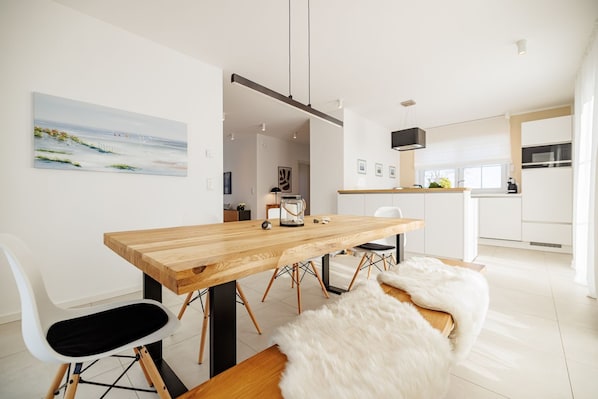Une cuisine moderne avec des meubles blancs, une table à manger en bois et une chaise blanche.