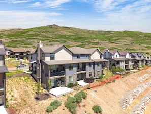 Un quartier résidentiel avec des maisons modernes, un ciel dégagé et un paysage vallonné en arrière-plan.