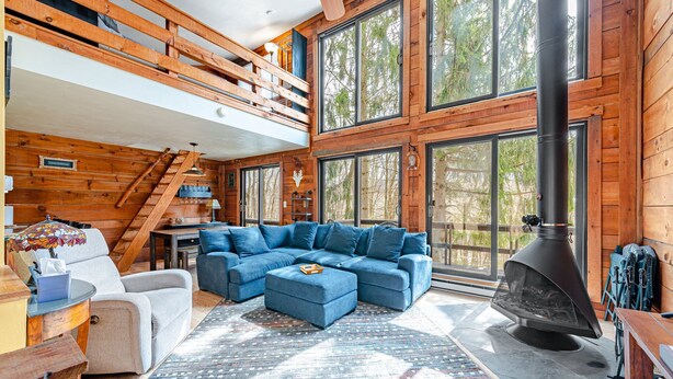 A cozy living room with a sectional sofa, a fireplace, and a loft bedroom with a wooden staircase. - 4 bed in Hidden Valley Resort, Slope View (Hidden Valley)