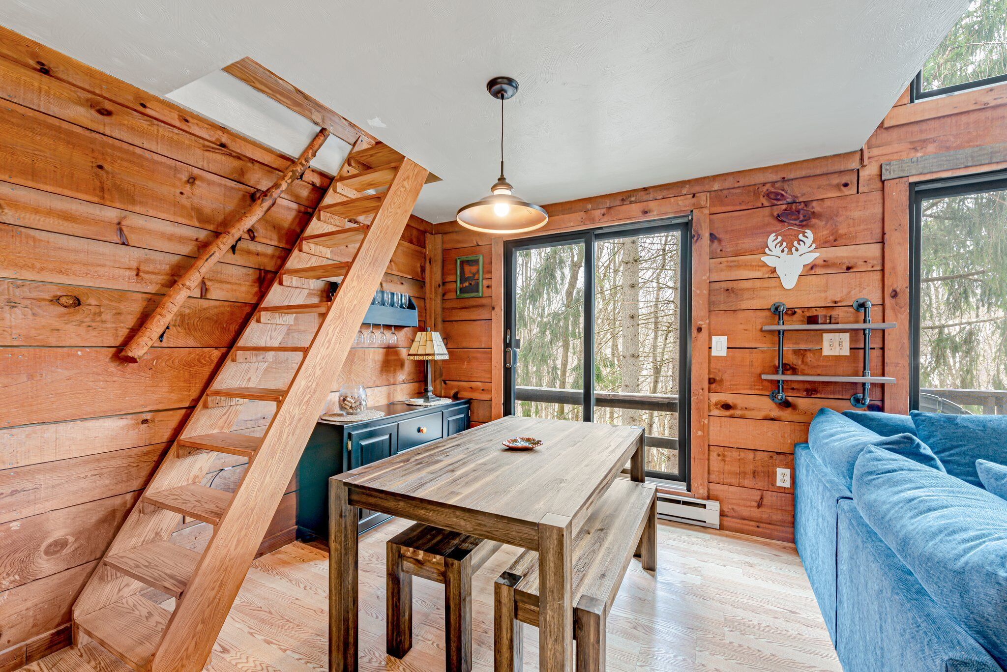 Un intérieur en bois avec un escalier en bois, une table à manger et un canapé bleu.