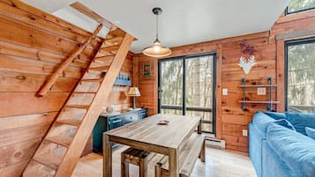 Un intérieur en bois avec un escalier en bois, une table à manger et un canapé bleu.