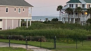 A coastal property with a two-story building featuring a balcony and a separate structure with a green roof.