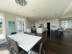 Una cocina amplia con electrodomésticos modernos, un comedor con una mesa grande y sillas, y vistas al exterior.