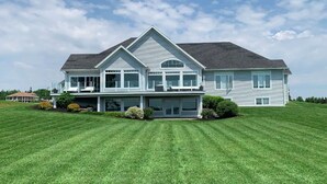 A large, two-story house with a prominent front porch, multiple windows, and a well-maintained lawn. - Executive Water Front Home With Steps To Water, 15 Mins to Downtown (Cornwall)