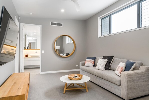 A modern living room with a grey sofa, a round mirror, and a wooden coffee table.