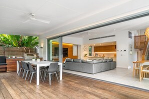 A modern kitchen with a built-in oven and a dining area with a white table and grey chairs.
