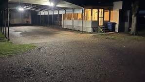 A covered outdoor area with a gravel path leading to a building with a metal roof and windows. - TE Ponderosa (Sardis)