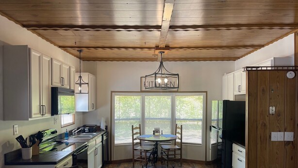 A kitchen with wooden ceiling beams, a dining table with chairs, a built-in oven, and a refrigerator. - TE Ponderosa (Sardis)