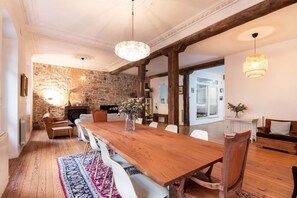 A dining area with a wooden table, white chairs, a stone wall, and a chandelier. - Amazing down town, near Guggenheim. Céntrico (BILBAO)