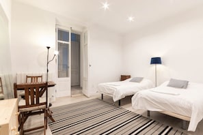 Una camera da letto con due letti, una sedia di legno, un tavolo e una lampada.