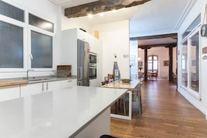 A kitchen with a large island, a refrigerator, and a dining area with chairs.