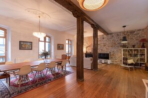 Un'ampia stanza con un tavolo da pranzo in legno, sedie, un divano, una televisione e una libreria.