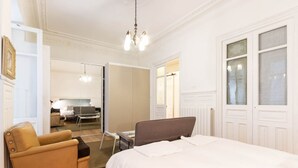 Quarto com cama, cadeira, escrivaninha e espelho.