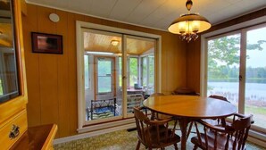 A dining area with a large round table and chairs, a chandelier, and a view of a lake through large windows.