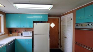 A compact kitchen with teal cabinets, a white refrigerator, a microwave, and a red oven. - Fiebing's Rustic/Remote Cabin on two Private Lakes (Traverse City)