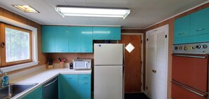 A compact kitchen with teal cabinets, a white refrigerator, a microwave, and a red oven.