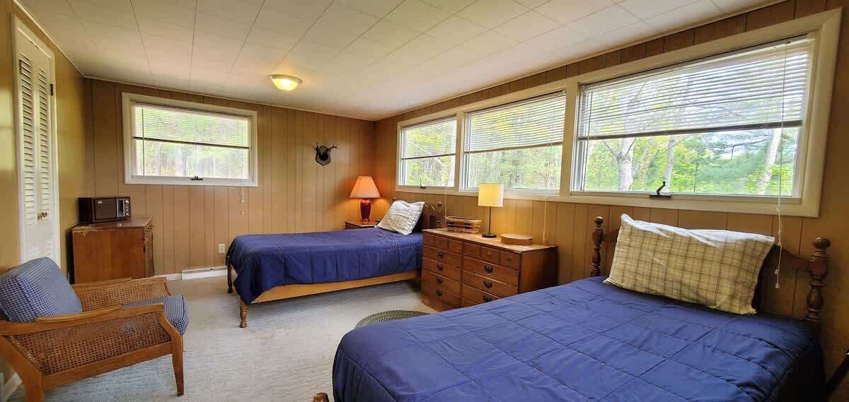 A bedroom with two beds, a dresser, a chair, and a television.