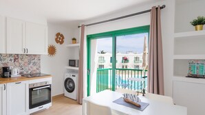 A compact kitchen with a washing machine, a coffee maker, and a dining area with a table and chairs.