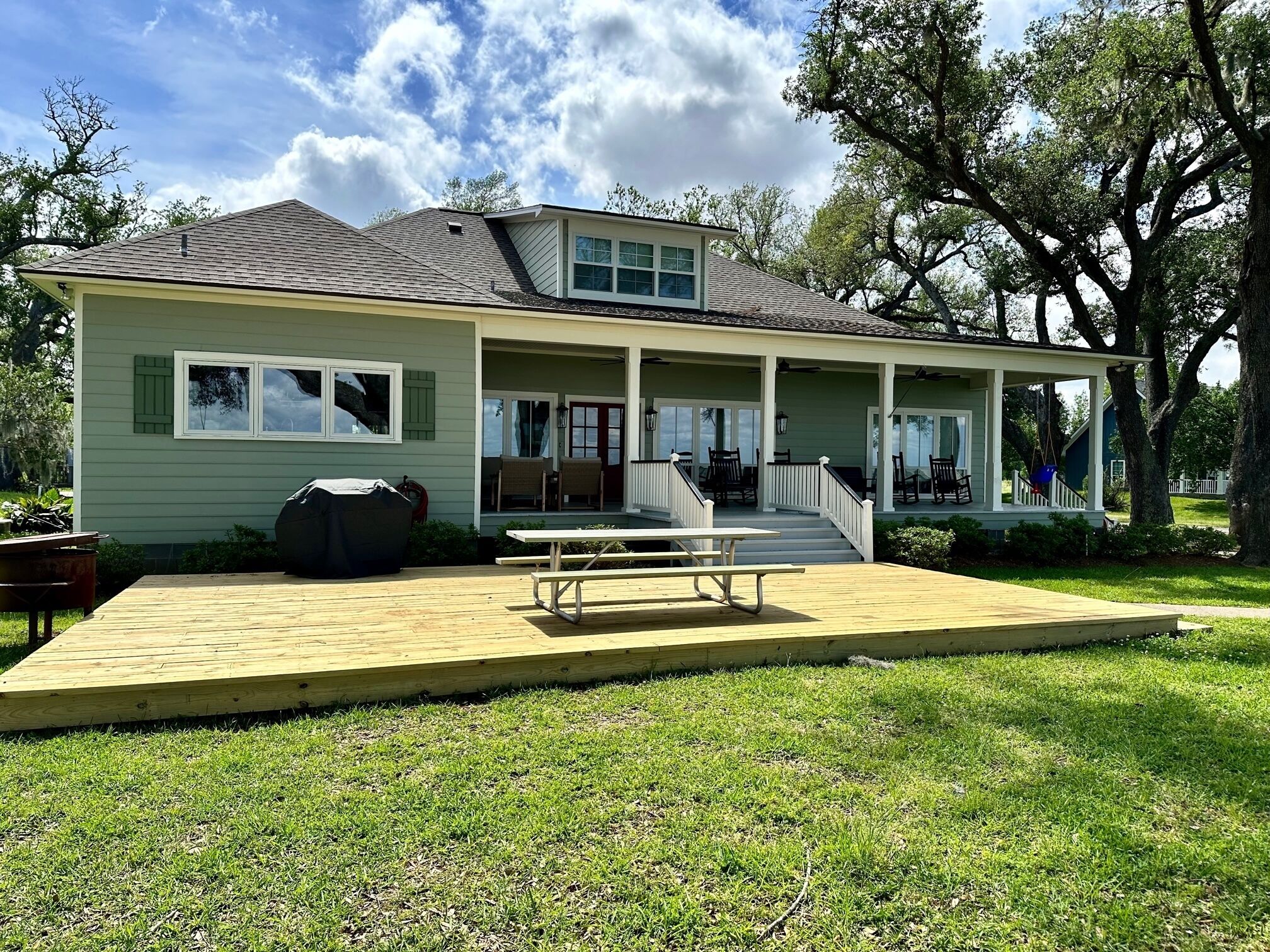 A two-story house with a covered porch, a barbecue area, and a picnic table.