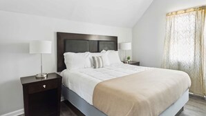 A neatly arranged bedroom with a large bed, two bedside tables, and a window with curtains. - Downtown Detroit 2BR | King, WiFi, Parking (Detroit)