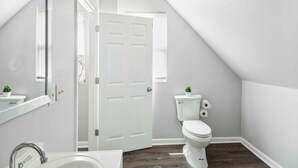 A modern bathroom with a white toilet, a sink, and a mirror. - Downtown Detroit 2BR | King, WiFi, Parking (Detroit)