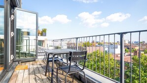 Een balkon met een tafel en stoelen, met uitzicht op een stadsbeeld.