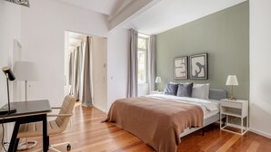 A bedroom with a bed, bedside tables, a desk, and a chair.