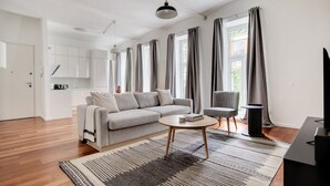 A modern living room with a grey sofa, a small round table, and a TV stand.