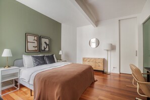 Un dormitorio moderno con cama, mesitas de noche, cómoda, silla y espejo.