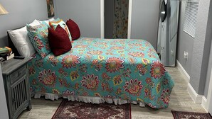 Quarto com cama, ventoinha no teto, porta, espelho e janela.