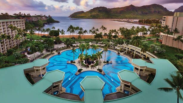 Ein Resort mit mehreren Schwimmbecken, einem Strand und einer Bergkulisse.
