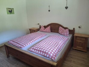 A double bed with checkered bedding, wooden headboard, two bedside tables, and a small bedside lamp.