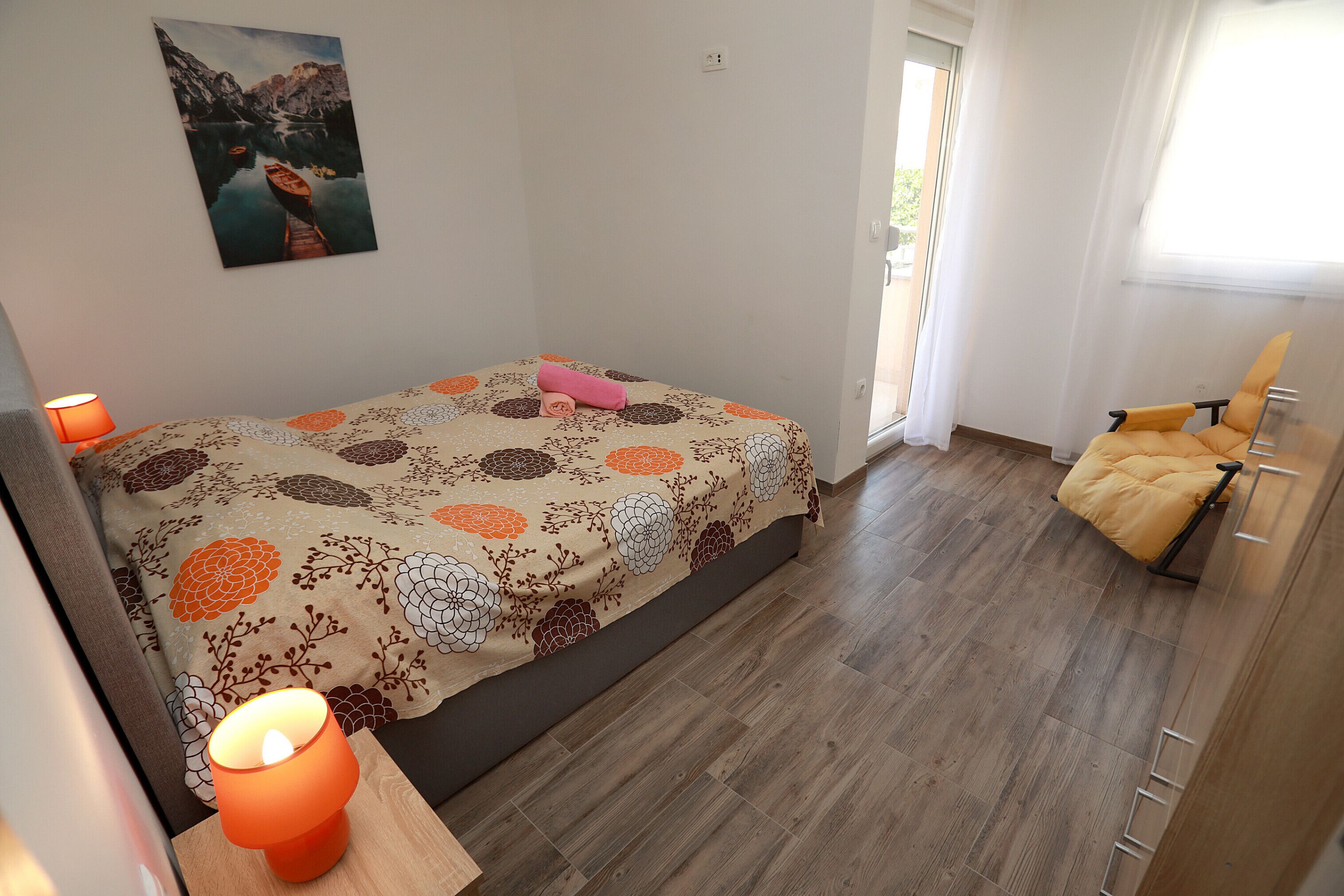 A bedroom with a bed, a chair, a lamp, and a painting on the wall.