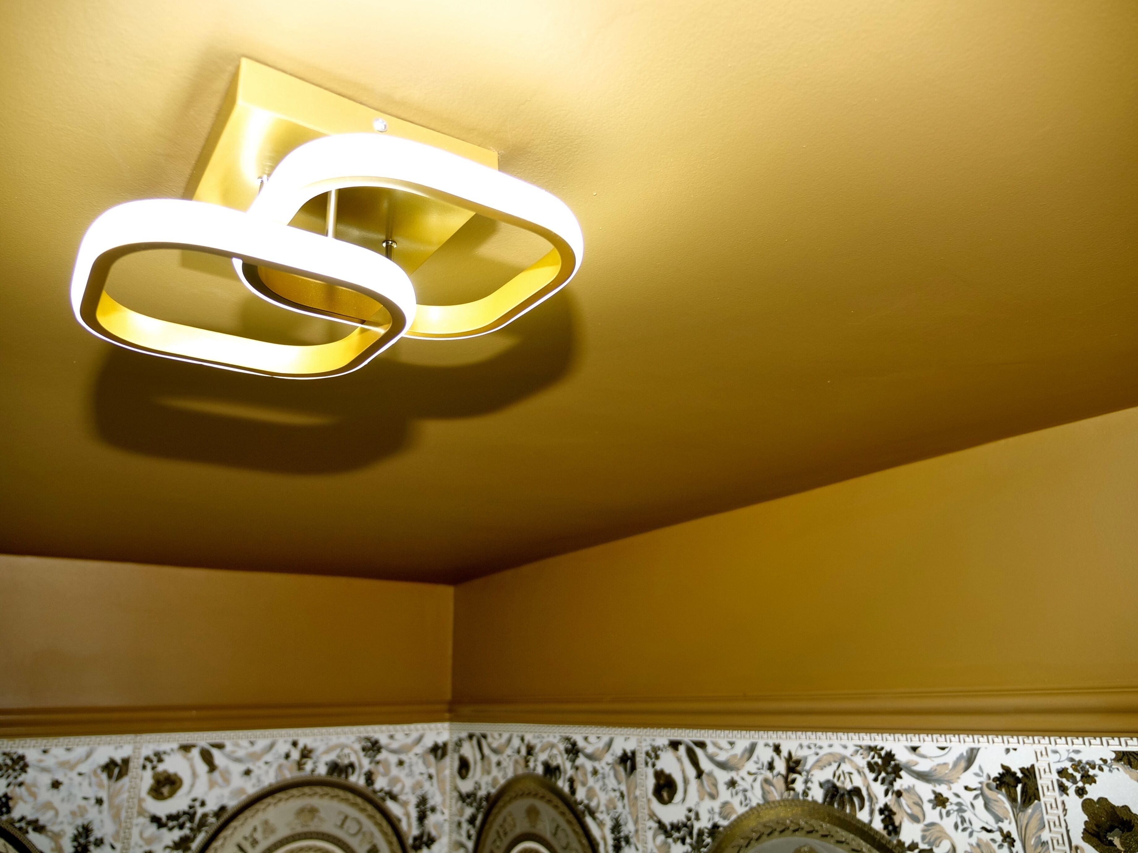 Un plafond agrémenté d’un luminaire moderne et un mur décoratif orné de carreaux à motifs.