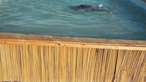 Piscina con muelle de madera en un paisaje seco y abierto.