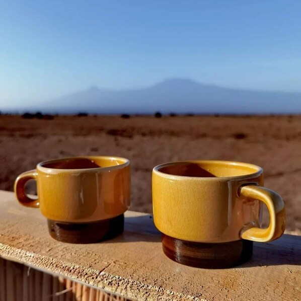 Two yellow ceramic mugs with handles on a wooden ledge.