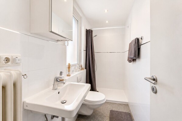 Une salle de bain moderne équipée d’un lavabo, de toilettes, d’une douche et d’un miroir.
