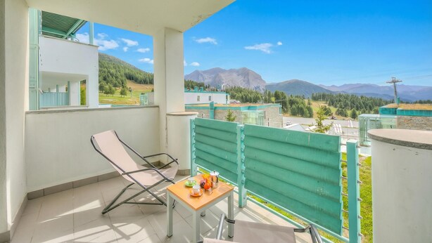 A balcony with a table and chairs, a view of mountains, and a clear sky. - Teleo 86 Ski In - Ski Out 50m, Sestriere, Italy (Sestriere)