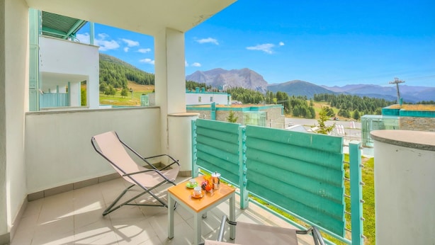 Un balcon avec une table, des chaises et une vue sur les montagnes.